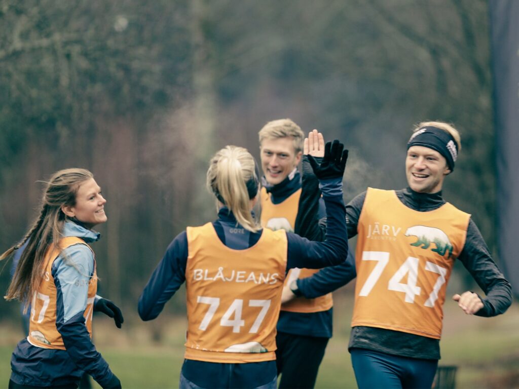 Lag i orange västar gör high five vid målgången