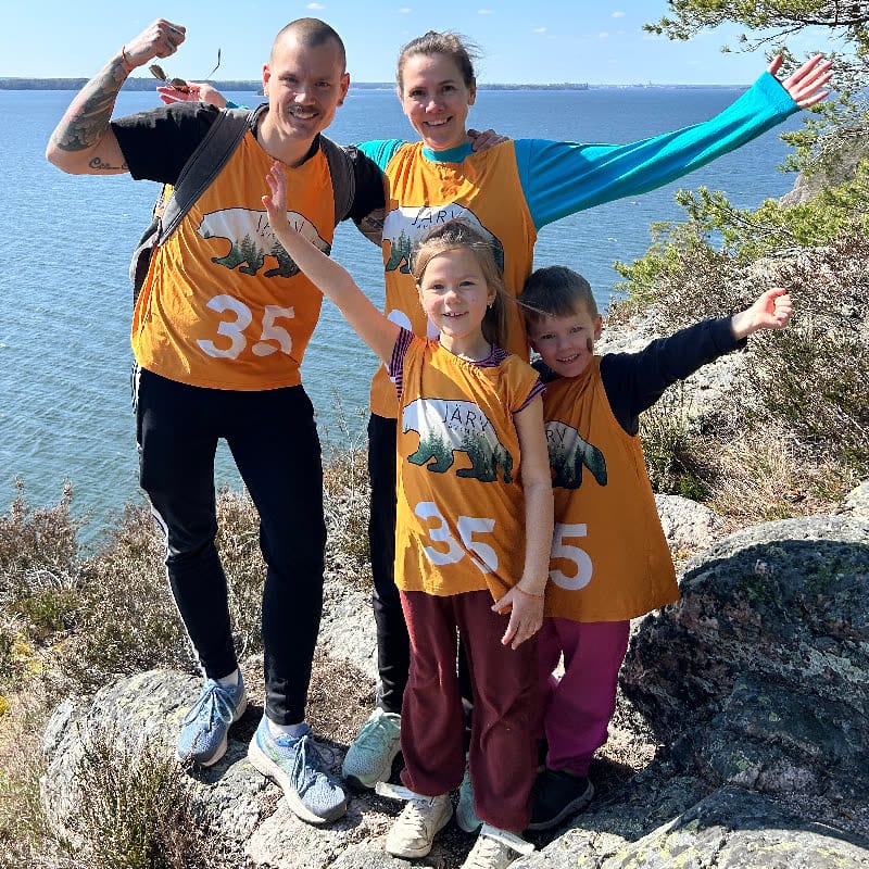 Barn och vuxna i orange västar jublar på klipporna vid havet